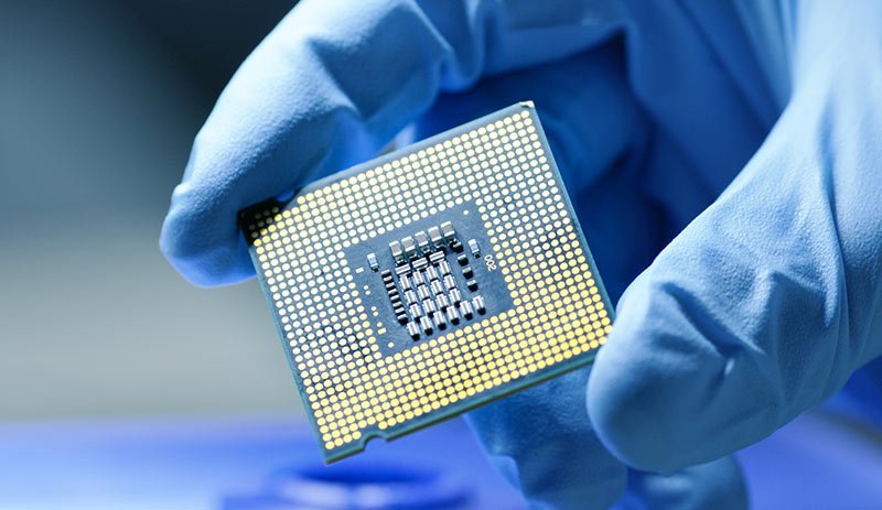 A close-up of a gloved hand holding a semiconductor